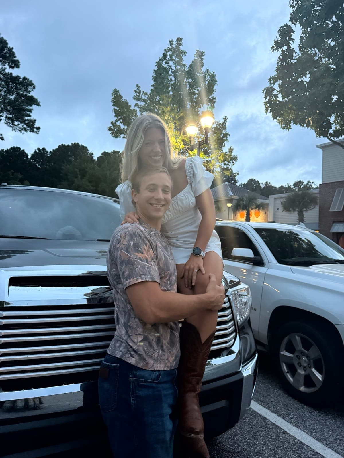 Emma sits on Will's hip in front of the truck beneath a glowing lamp post